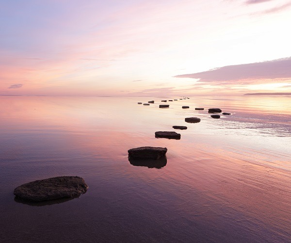 Large rocks in single file heading out towards the horizon under the sunset