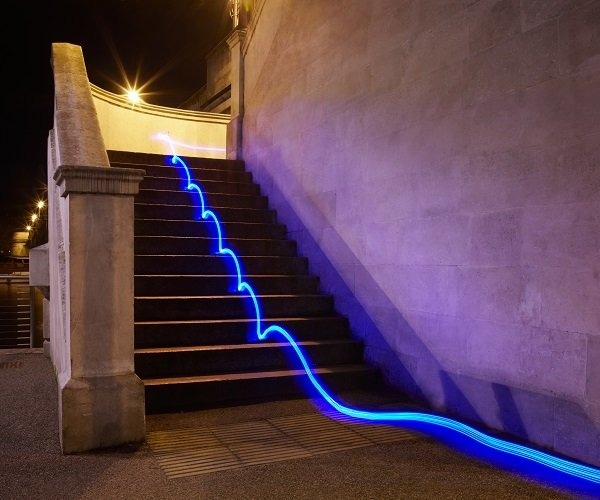 Blue beam of light running parallel to staircase at night